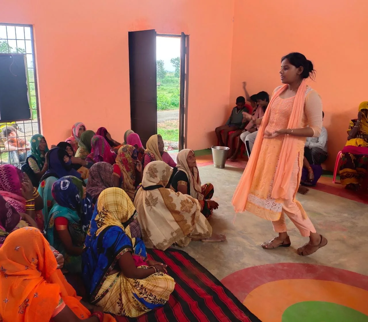 A woman leading an awareness session with women from the community